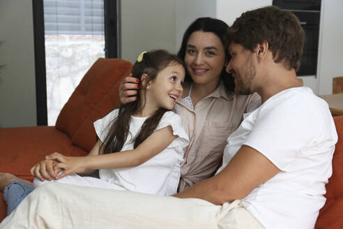 Lächelnde Frau mit Familie, die zu Hause auf dem Sofa sitzt - SYEF00433