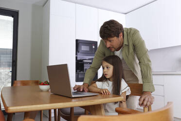 Vater hilft einem Mädchen bei der Benutzung eines Laptops zu Hause - SYEF00461