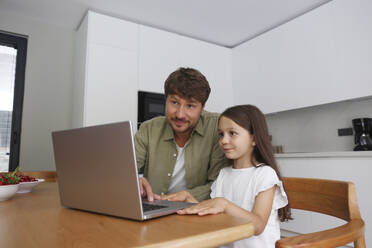 Vater und Tochter teilen sich einen Laptop zu Hause - SYEF00463