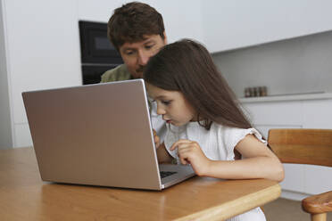Mädchen lernt mit Vater zu Hause den Umgang mit dem Laptop - SYEF00465