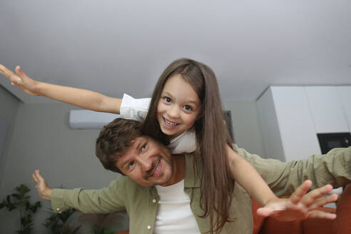 Smiling man carrying daughter on shoulders at home - SYEF00467