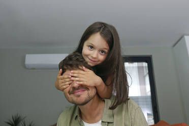 Lächelnde Tochter, die die Augen des Vaters zu Hause bedeckt - SYEF00468