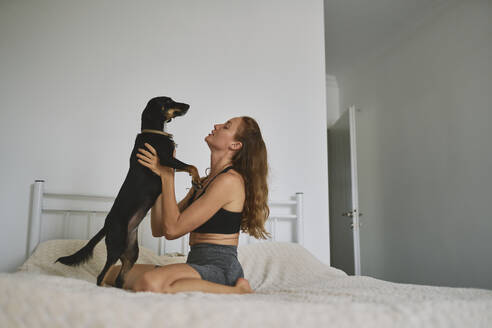 Happy woman embracing dog at home - ANNF00322