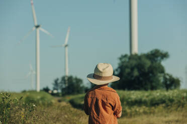 Boy wearing hat standing in field on sunny day - VSNF01079