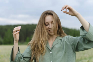 Verspielte junge Frau mit langen blonden Haaren auf einem Feld - SEAF01979