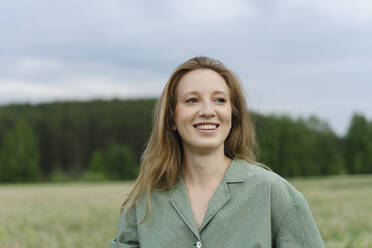 Lächelnde junge Frau mit blondem Haar auf einem Feld - SEAF01982