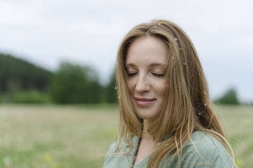 Lächelnde junge Frau mit geschlossenen Augen auf einem Feld - SEAF01992