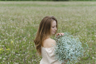 Junge Frau hält Wildblumenstrauß auf einem Feld - SEAF02001
