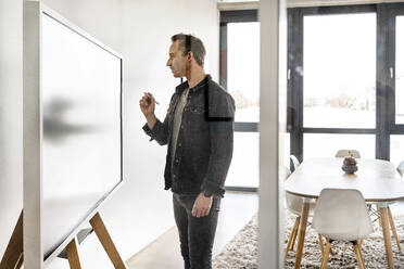 Geschäftsmann mit digitalisiertem Stift bei der Arbeit an einem interaktiven Whiteboard - PESF03907