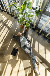Businessman lying on floor in office - PESF03922
