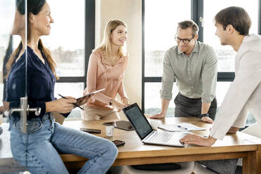 Happy business colleagues having discussion together in office - PESF03924