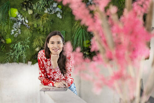 Happy businesswoman with tablet PC leaning on wall - PESF03930