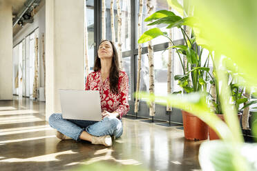 Businesswoman sitting with eyes closed on floor - PESF03938