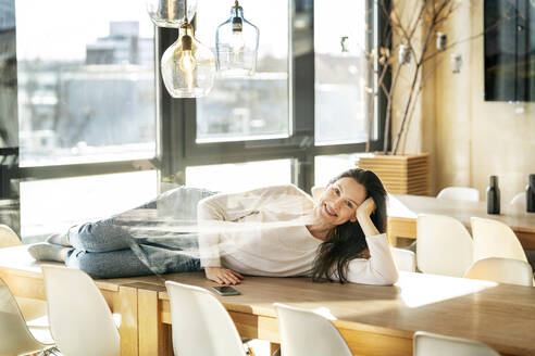 Happy businesswoman lying on table seen through glass - PESF03972