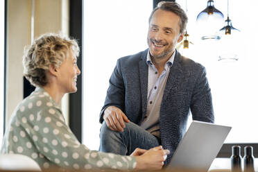 Smiling business colleagues discussing together about work in office - PESF03983