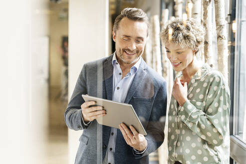 Happy business colleagues discussing over tablet PC - PESF03990