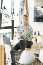 Smiling businesswoman with digital tablet sitting at table - PESF03996