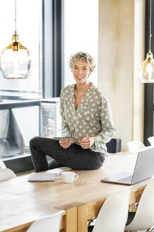Lächelnde blonde Geschäftsfrau mit Tablet-PC sitzend - PESF03997