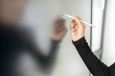 Hand einer Geschäftsfrau, die mit einem digitalisierten Stift auf einem interaktiven Whiteboard schreibt - PESF04004