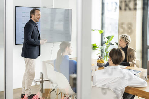 Happy businessman giving presentation with colleagues in office - PESF04018