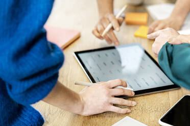 Business colleagues having discussion over tablet computer on table - PESF04034