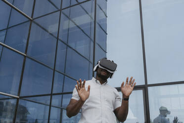 Geschäftsmann mit Virtual-Reality-Simulator vor einem Glasgebäude - OSF01689