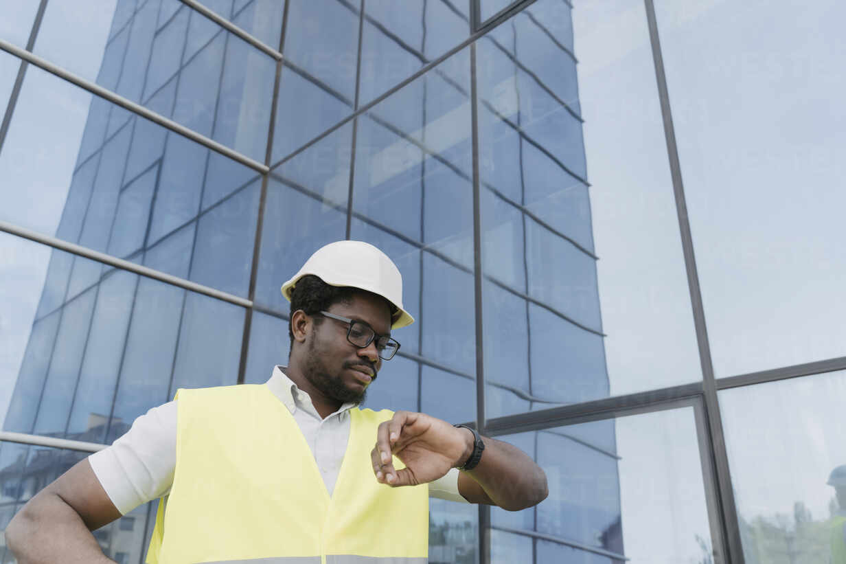 Selbstbewusster Bauarbeiter mit reflektierender Kleidung und Schutzhelm auf  einer Baustelle, lizenzfreies Stockfoto