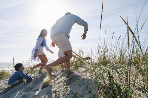 Familie spielt am Strand an einem sonnigen Tag - ASGF03748