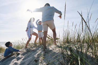 Parents playing with children at beach on sunny day - ASGF03749