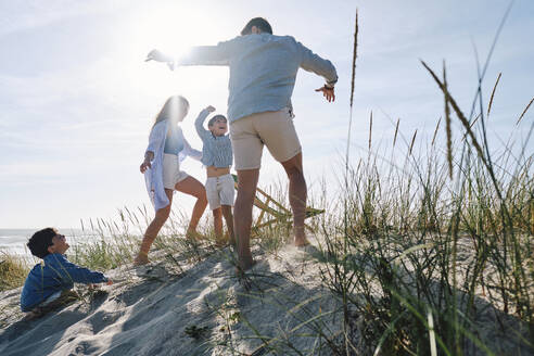 Eltern spielen mit Kindern am Strand an einem sonnigen Tag - ASGF03749