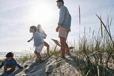 Eltern und Kinder vergnügen sich am Strand an einem sonnigen Tag - ASGF03751