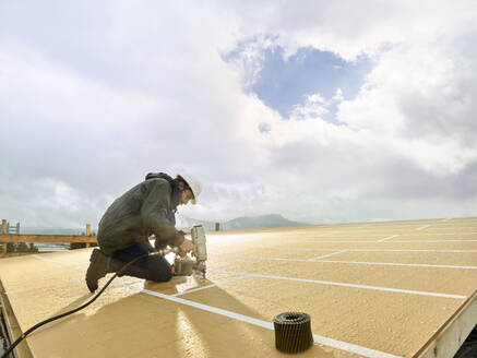 Zimmermann mit Nagelwerkzeug auf einem Holzdach auf der Baustelle - CVF02421