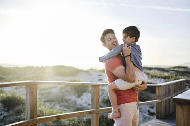 Vater trägt seinen Sohn am Geländer der Strandpromenade - ASGF03781