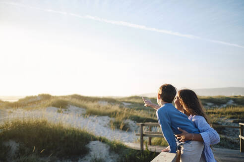 Mother showing landscape to son from boardwalk at beach - ASGF03789