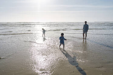 Vater genießt mit Kindern am Strand an einem sonnigen Tag - ASGF03796