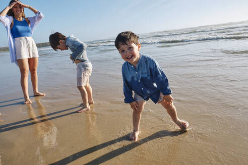 Lächelnder Junge genießt mit Familie am Strand - ASGF03802