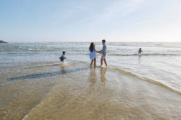 Familie genießt im Meerwasser am Strand an einem sonnigen Tag - ASGF03804
