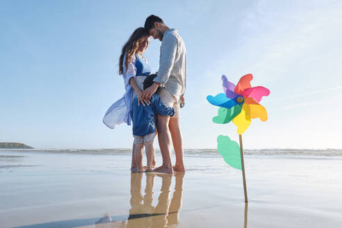 Pinwheel toy at beach with family standing together in background - ASGF03814