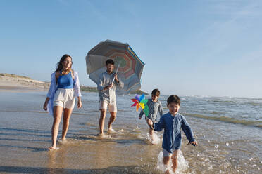 Eltern spazieren mit Kindern im Wasser am Strand - ASGF03819