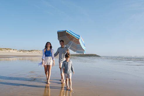 Eltern gehen mit ihrem Sohn am Strand spazieren - ASGF03822