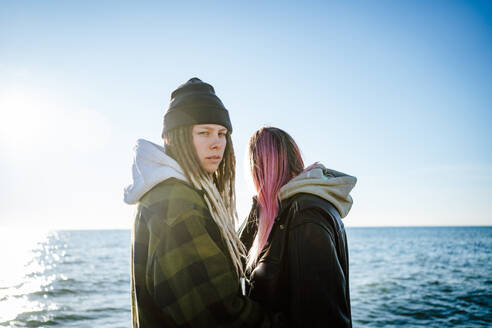 Zwei junge Frauen stehen zusammen am Meer - MDOF01334