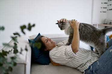 Glückliche Frau streichelt und spielt mit Katze zu Hause - ANNF00328