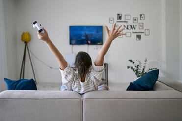 Glückliche Frau gewinnt in einem Videospiel und sitzt mit erhobenen Armen zu Hause - ANNF00341