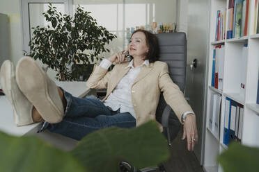 Thoughtful senior businesswoman relaxing on chair in office - OSF01702