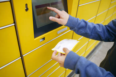 Junge mit Fahrkarte, der die Daten auf dem Bildschirm des Paketfachs eingibt - NJAF00356