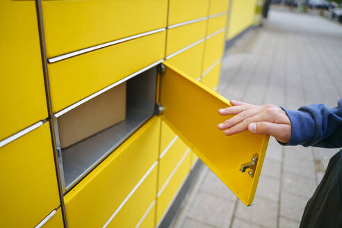 Hand eines Jungen beim Öffnen eines Paketfachs - NJAF00360