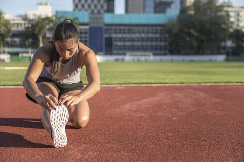 Junge Frau trainiert auf einem Sportplatz - IKF00849