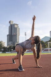 Young woman exercising in sports field - IKF00855