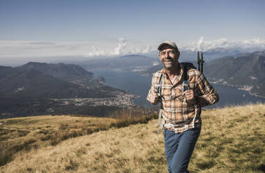 Glücklicher Mann beim Wandern auf einem Berg an einem sonnigen Tag - UUF28888