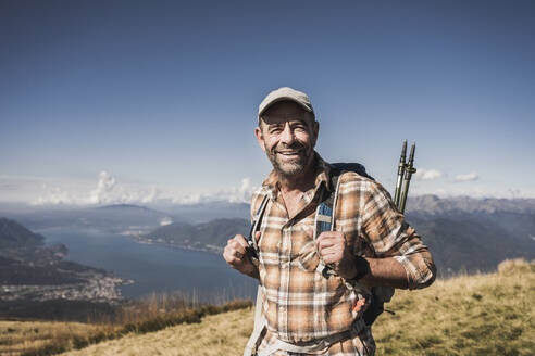 Glücklicher Wanderer auf dem Berg stehend an einem sonnigen Tag - UUF28890